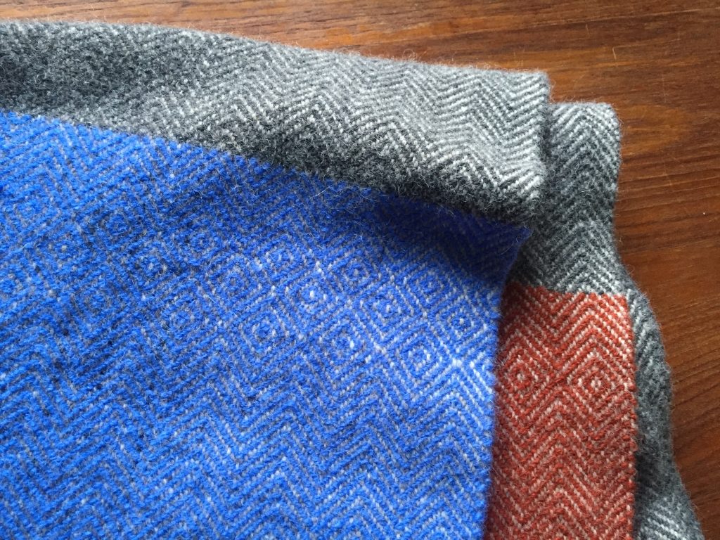 Detail of colorblocked twill poncho with birdseye details